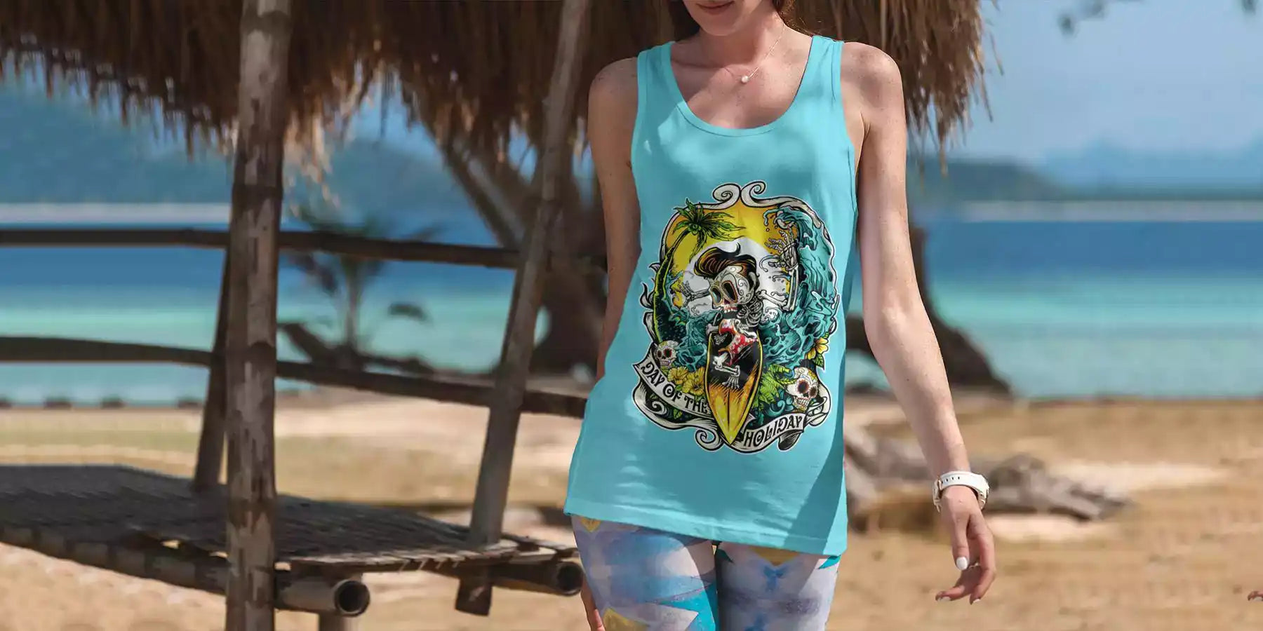 Woman is wearing a printed teal colour tank top. The tank top design is a skeleton riding a surfboard. Sea, sand and palms on the background
